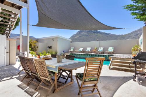 a patio area with a table, chairs and a patio table at The Beach House Guest House in Hout Bay