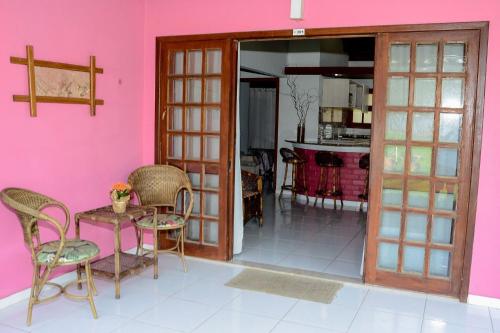 a room with a pink wall and a table and chairs at Chalés Saint Germain in Florianópolis