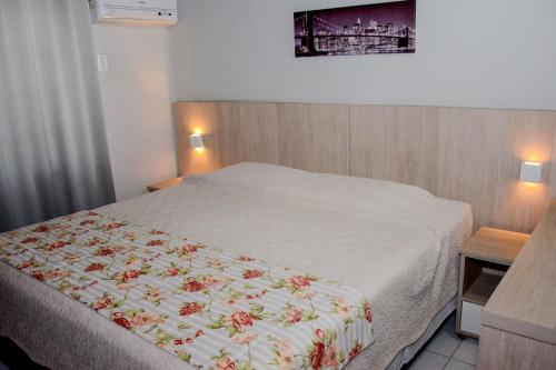 a bedroom with a bed with a floral blanket on it at Chalés Saint Germain in Florianópolis