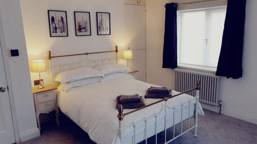 Un dormitorio con una cama blanca con dos bolsas. en The Old Bank Beautiful Cotswold House with Huge Garden, en Mickleton