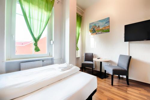 um quarto com uma cama e duas cadeiras e uma janela em Hotel B1 em Berlim