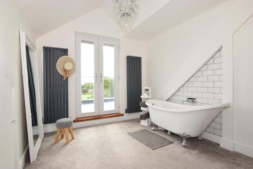a white bathroom with a tub and a window at Corbiere in Shanklin