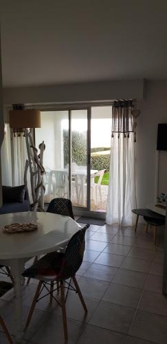 un salon avec une table et des chaises et un balcon dans l'établissement Les Rochers de Vallières, Appartement de 35 m2 avec 1 chambre, Terrasses, Jardin 140 m2, Vue panoramique face à l'Océan !, à Saint-Georges-de-Didonne
