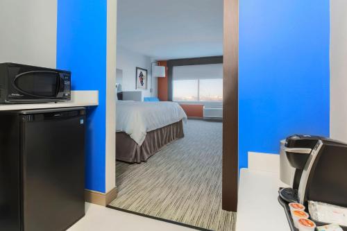 a hotel room with a bed and a tv at Holiday Inn Express & Suites Chicago O'Hare Airport by IHG in Des Plaines