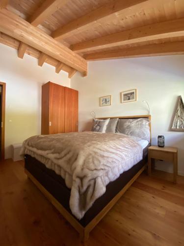 a bedroom with a large bed with a wooden ceiling at Chalet Conthey in Zermatt