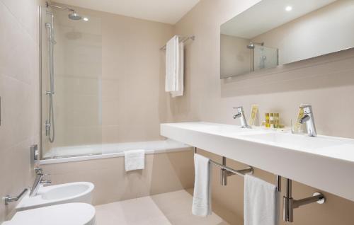 a bathroom with two sinks and a shower and a toilet at Eurostars Mar de Vigo in Vigo