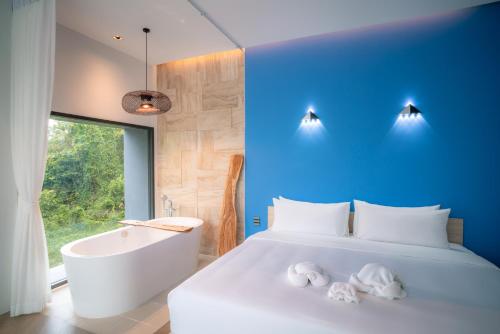 a bedroom with a white bed and a tub and a bath tub at Chomdao Maikhao in Ban Bo Sai Klang