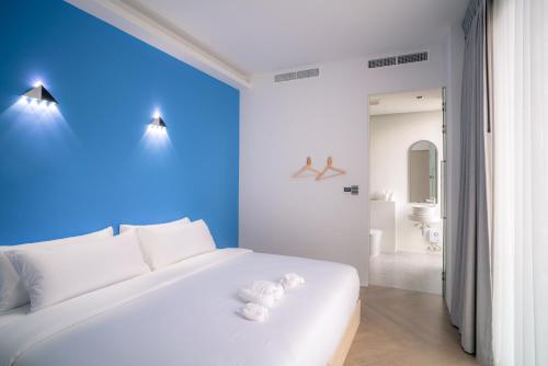 a bedroom with a white bed and a blue wall at Chomdao Maikhao in Ban Bo Sai Klang