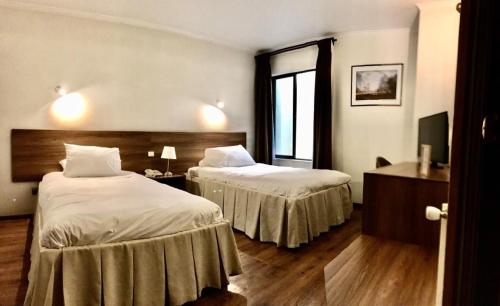 テムコにあるKU Hotel Turismo Temucoのベッドが2つと窓があるホテルの部屋