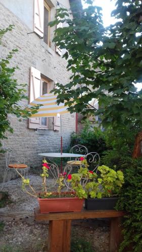 une table avec un parapluie et des plantes en pot dans l'établissement petite maison au paradis, à La Neuvelle-lès-Scey