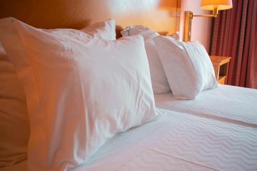 a bed with white pillows on top of it at Hotel Regua Douro in Peso da Régua