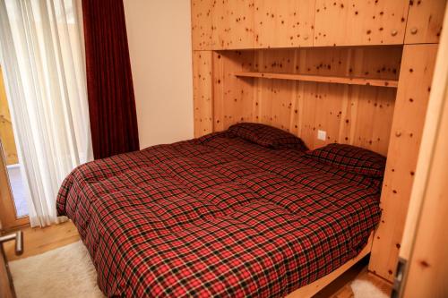 um quarto com uma cama e uma parede de madeira em Ca del Forno St Moritz em Maloja