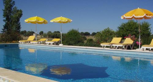 a group of yellow chairs and umbrellas next to a swimming pool at Monte Da Serralheira Agro Turismo in Évora