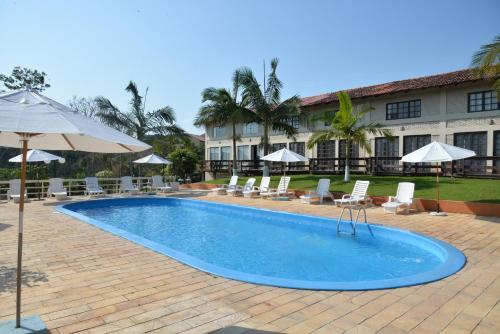 uma piscina com cadeiras e guarda-sóis ao lado de um edifício em Morro do Sol Hotel & Eventos em Porto Belo