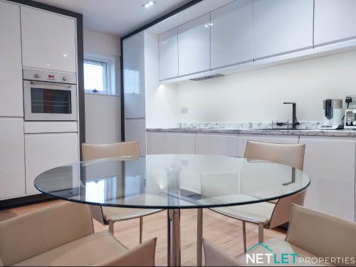 a kitchen with a glass table and chairs at Orion House - Luxury Apartment overlooking Milford Marina, Pembrokeshire in Milford Haven