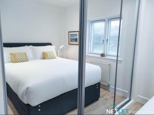 ein Schlafzimmer mit einem weißen Bett und einem Fenster in der Unterkunft Orion House - Luxury Apartment overlooking Milford Marina, Pembrokeshire in Milford Haven