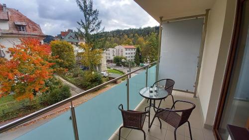 a balcony with a table and chairs and a view at Apartament DOMINO Krynica Zdrój in Krynica Zdrój