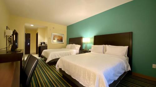 a hotel room with two beds and green walls at Holiday Inn Express Hotel & Suites Orlando East-UCF Area, an IHG Hotel in Orlando