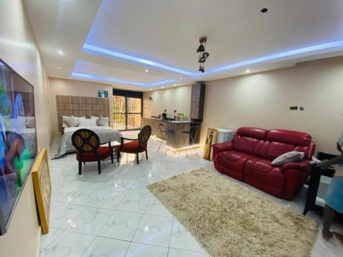 a living room with a red couch and a bed at Trendy apartments in Entebbe