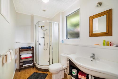 a white bathroom with a shower and a sink at Kumeu Kottage in Kumeu