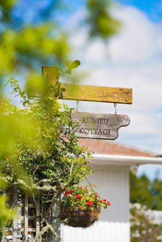 una señal en el lado de una casa con flores en Kumeu Kottage, en Kumeu