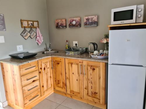 a kitchen with wooden cabinets and a white refrigerator at Forest Hill Country Lodge in Piet Retief
