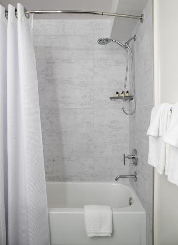 a bathroom with a shower and a white tub at The Domain Hotel in Sunnyvale