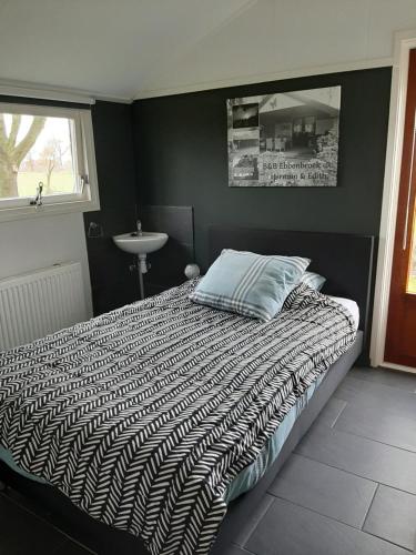 a bedroom with a bed and a sink and a window at gastenverblijf Ebbenbroek in Bruchterveld