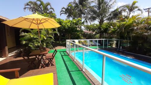 a balcony with an umbrella and a swimming pool at Pousada Palhocinha Garopaba in Garopaba