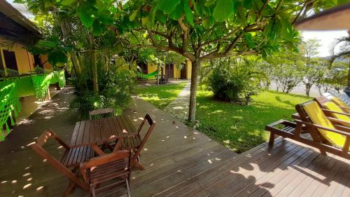 a wooden deck with two benches and a tree at Pousada Palhocinha Garopaba in Garopaba