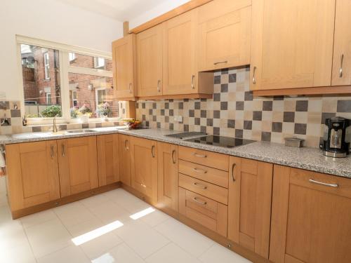 a large kitchen with wooden cabinets and a window at 1A Chantry Place in Morpeth