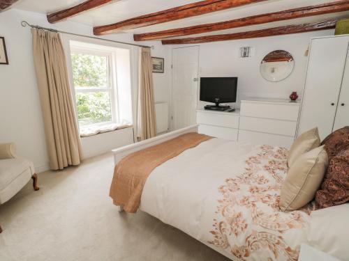 a white bedroom with a bed and a television at 1A Chantry Place in Morpeth