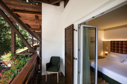 a bedroom with a balcony with a bed and a chair at Hotel Medil in Campitello di Fassa