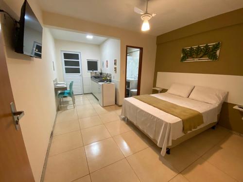 a bedroom with a bed and a kitchen and a table at Residencial Lúpulos in Angra dos Reis