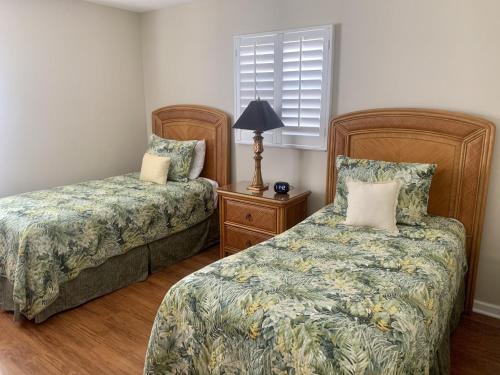 a bedroom with two beds and a lamp at Island House Beach Resort 28 in Point O'Rocks