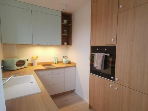 a kitchen with wooden cabinets and a counter top at Apartament uTymka in Słupsk