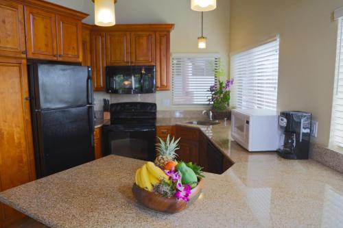 a kitchen with a black refrigerator and a bowl of fruit on a counter at Club Wyndham Ka Eo Kai in Princeville