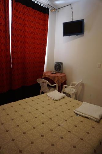 a bedroom with a bed and a table and a television at Hostal Camiluz in Nazca