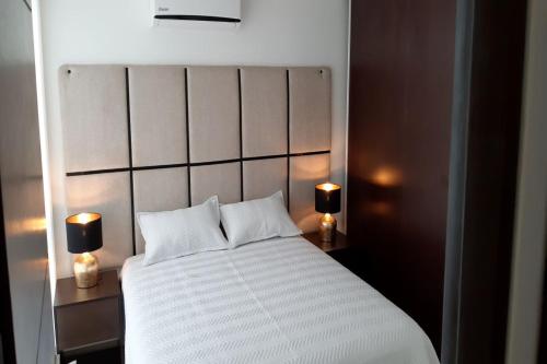 - une chambre avec un grand lit blanc et deux lampes dans l'établissement Elegante apartamento en Condominio Baruc II, à Santa Cruz de la Sierra