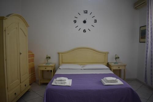 a bedroom with a bed with a clock on the wall at In Riva al Mare in Gela