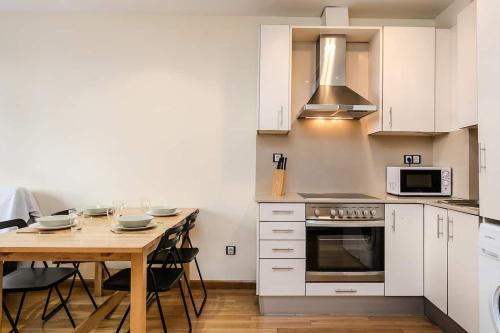 a kitchen with white cabinets and a wooden table at Homenfun Barcelona Poble Sec in Barcelona
