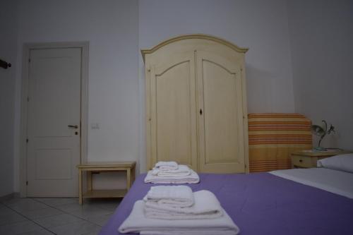 a bedroom with a bed with purple sheets and white towels at In Riva al Mare in Gela