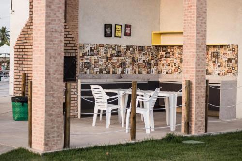 eine Terrasse mit zwei weißen Stühlen und einem Tisch in der Unterkunft Muro Alto Condomínio Club in Porto De Galinhas