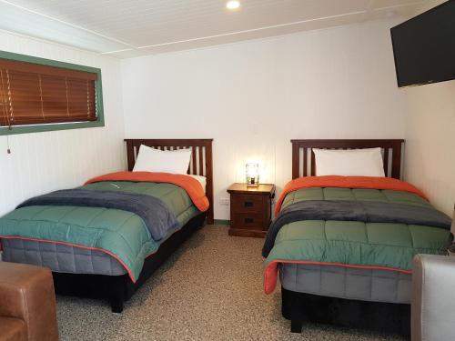 - une chambre avec deux lits, une table et une chaise dans l'établissement Millers Flat Holiday Park, à Millers Flat