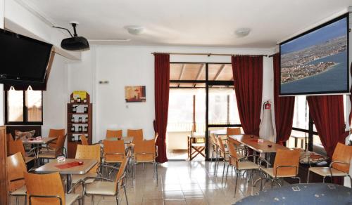 une salle à manger avec des tables, des chaises et un grand écran dans l'établissement Hotel Ballas, à Agria