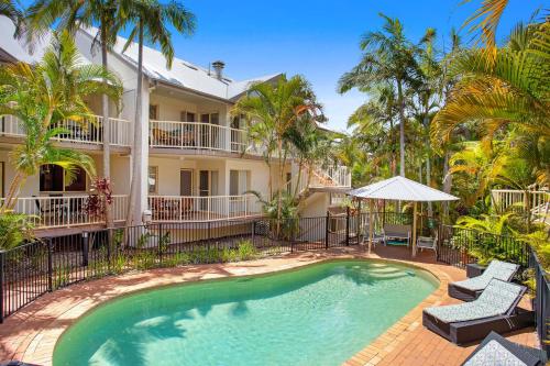 a swimming pool in front of a house with palm trees at Mariner Bay Apartments in Byron Bay