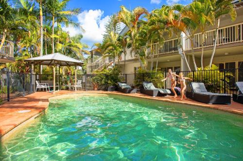 a swimming pool with people standing next to a house at Mariner Bay Apartments in Byron Bay