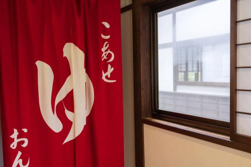a red curtain with asian writing on it next to a window at Bunanoyado Koase in Aga