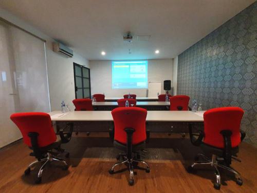 a conference room with a large table and red chairs at Liberty Hotel Thamrin Jakarta in Jakarta