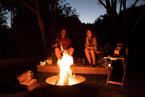 two women sitting around a fire in a yard at The Barn Cabins & Camp in Marahau